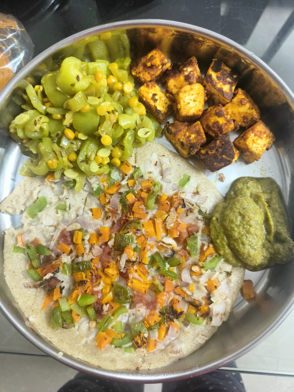A vegetable-topped millet uttapam with green chutney, pan-roasted paneer cubes, and a ridge gourd stir-fry with dal