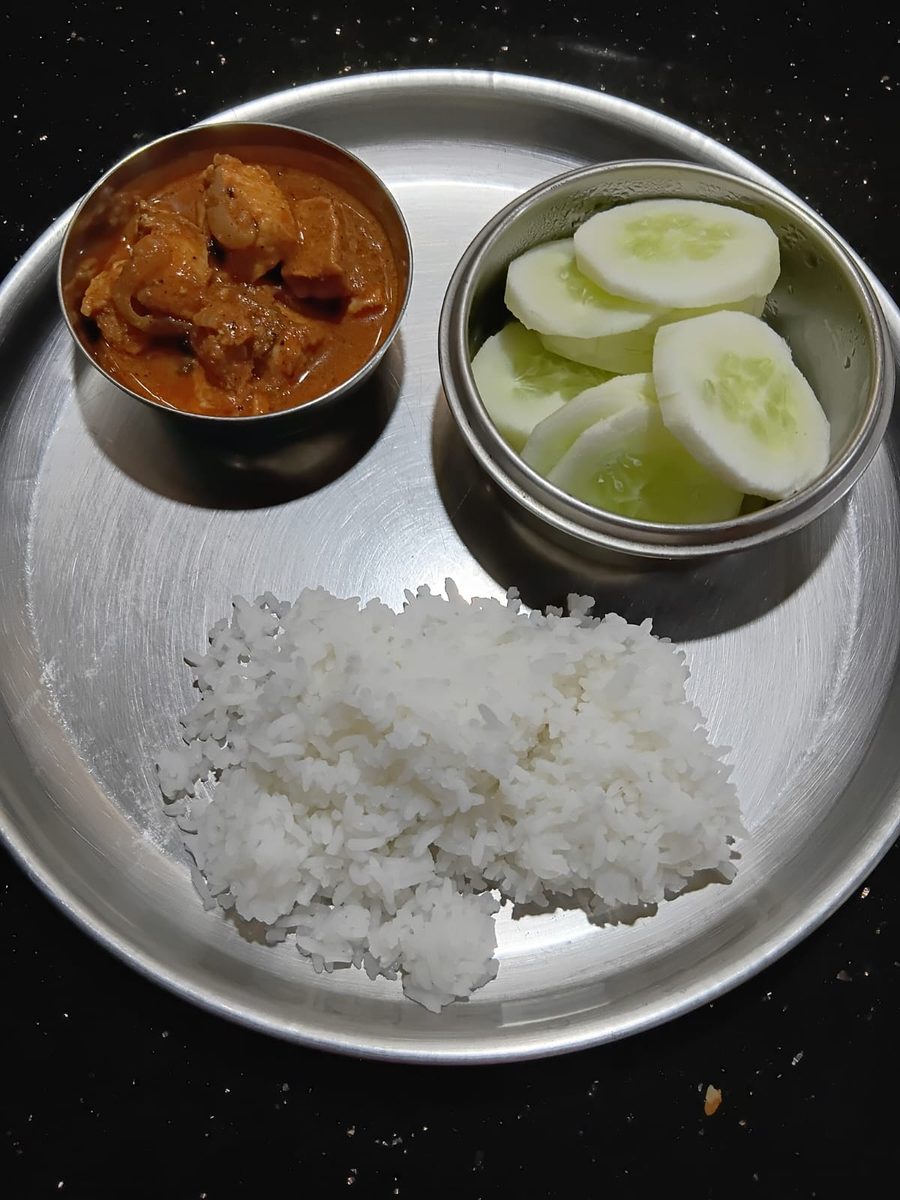 Chicken curry with a measured portion of rice and cucumber on the side