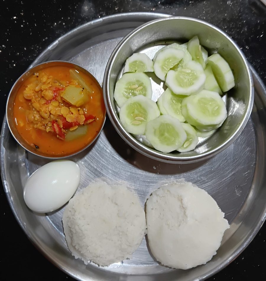 A plate of idli with a boiled egg, dal, and cucumber slices